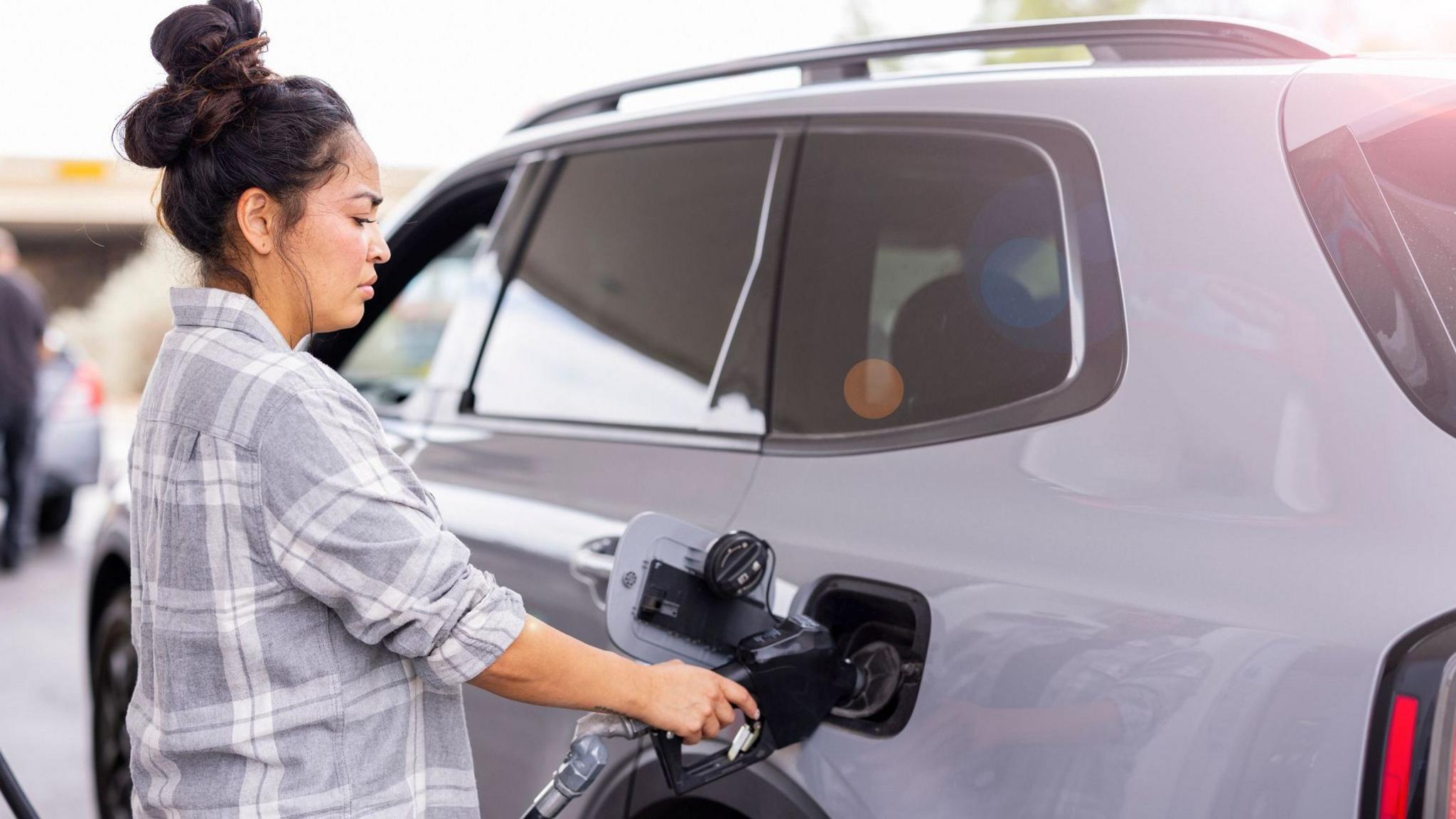 Woman fills up her car with fuel at forecourt